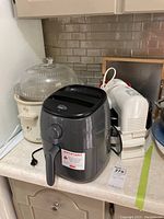 Dash Air Fryer on countertop, showing front and side view with power cord and timer dial.