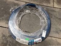 Coiled blue Superpex hose wrapped in plastic with label and length/diameter details visible.