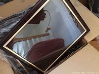 Black and gold picture frame showing reflective glass and details of the frame's construction.