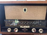 Front view of the vintage Ducretet Thomson radio showing woven fabric speaker grille, wooden casing, knobs and frequency display.
