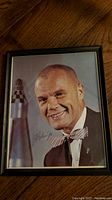 Framed signed photograph of John Glenn Jr. in bow tie.