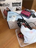 Overview of the lot showing the Shiatsu neck massager box and device, The Comfy fleece wrap packaging, and shoe grips with a white cloth.