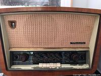 Front view of the vintage Radiola radio showing wooden cabinet and fabric speaker grille with the Radiola badge.