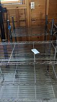 Metal wire storage shelf with wire mesh shelves and metal poles in garage environment.