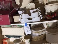 White Lenox china pieces in quilted storage carriers, assorted plate stacks and serving bowls visible