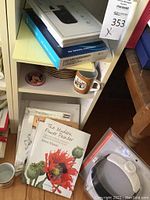 Fox-themed dishes and tea mugs on shelf with books and magnifying headband box.