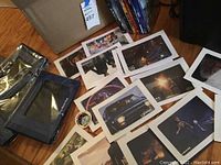 Photo showing Disney Movie Club binders, unopened plastic sleeves and various printed Disney movie art pieces laid out on the floor.