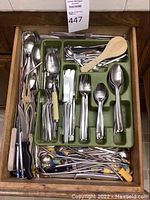 Wooden drawer with green utensil tray and loose items