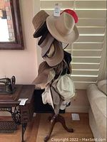 Full view of the tall wooden and metal hat rack featuring a variety of hats.