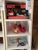 Shelf featuring Lego sets including boxed items and a large pink Lego-shaped pencil box, decorative boxes, and a Snoopy DVD case