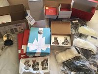 Overview photo showing Lenox ornaments in original packaging, unopened Christmas cards, Outlander stockings, and some of the snow globes.