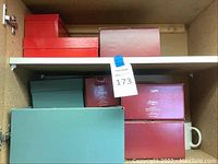 Red and teal boxes stacked on shelf labelled as containing Lenox and related items.