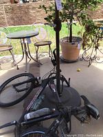 Photo of the black Specialized HR Pro bicycle on its side beside the patio area, showing frame, wheels, and base of umbrella stand.