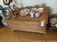 Wooden storage chest closed with some decorative plates and items on top (not included)