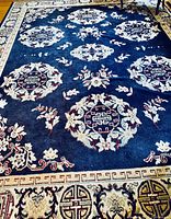Wide shot of blue Asian-style rug showing medallion and floral border pattern