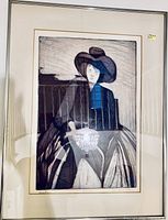 Framed black and white print of a woman wearing a large hat, sitting, signed at art bottom