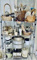 Full view of the shelving rack holding kitchen appliances and baskets with utensils, including Cuisinart food processor and rice cooker.