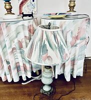 Single small lamp with white marble base, brass detailing and pastel floral fabric shade.