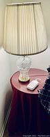Crystal table lamp on round table with red cloth, showing lamp base and pleated shade