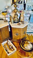 Two wooden end tables with light marble tops, wood goblet, small wooden ship sculpture, a chipped wooden bird, and wooden bowls placed in white tray. Wooden lazy Susan stand also visible.