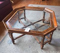 Overall view of the octagonal coffee table showing wood frame, glass top, and carved legs