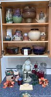 Full view of crockery and figurines arranged in wooden cabinet and on countertop below.