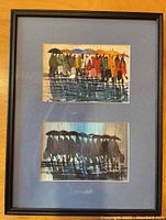 Full framed artwork showing both watercolor paintings matted together with blue matting and enclosed in a black frame.