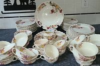 Full view of Spode china set including stacked plates, cups, saucers, and creamers on a countertop