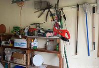 Full view of cordless weed wacker, garden tools, and shelves with containers and boxes