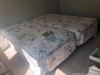 Two twin-width mattresses with floral covers on adjustable base