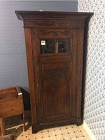 Front view of oak jam cabinet showing entire door, glass panel, carved details and molding.