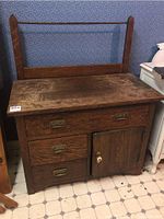 Front view of the antique oak washstand showing three drawers on the left, one drawer at the top center, small cabinet door on the right with white ceramic knob, and rectangular mirror mounted on back with wooden frame.