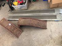 Two galvanized ramps with diamond-pattern surface, two red wheel chocks and white bin partially shown