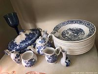 Photo of the entire set showing tureen, teapot, creamer, sugar bowl, small vases and stack of soup bowls with blue and white pattern.
