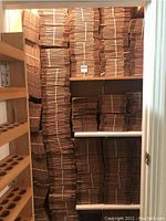 Shelves filled with large stacks of bundled cardboard boxes showing quantity and storage condition.
