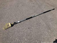 Full length image of the 24-foot Docapole extension pole with yellow metal fruit picker basket attached at one end, showing black foam grip areas.