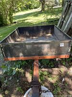 Front view of steel garden trailer showing box interior, tongue and coupler with chain
