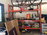 Deep orange shelving unit with particle board shelves loaded with tools and toys