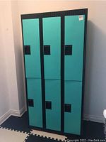 Front view of six lockers assembly showing three columns and two rows with black frame and turquoise doors