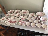 Wide view of Masons Ironstone dinnerware and serveware arranged on table showing plates, bowls, cups, platter, and butter dish.