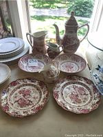 Overview of pink and white china collection showing teapot, pitchers, plates, and bowls