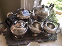 Full view of silver plated tea service on ornate tray with all pieces visible: teapot, coffee pot, sugar bowl, creamer, waste bowl