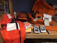 Overview of chainsaw, case, safety gear, gloves, spare chains and paperwork