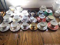 Overview of all fifteen tea cup and saucer sets on wooden table