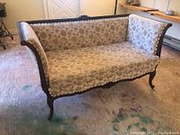 Front left angle view of settee showing carved wooden frame and floral upholstery
