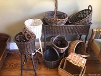 Full view of the wicker planter stand group including the white and dark brown planters and several baskets on the floor