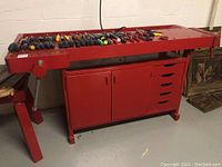 Red painted workbench along with multiple screwdrivers laid out on top surface.