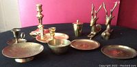 Full set of brass/copper items on display including trays, candle holders, deer figurines, bowl, and container