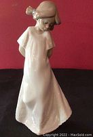 Front view of the Nao figurine showing the young girl standing with head slightly bowed and hands behind back