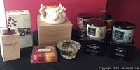 Wide view showing all candles, wax melts, and candle holders on black background with red wall behind.